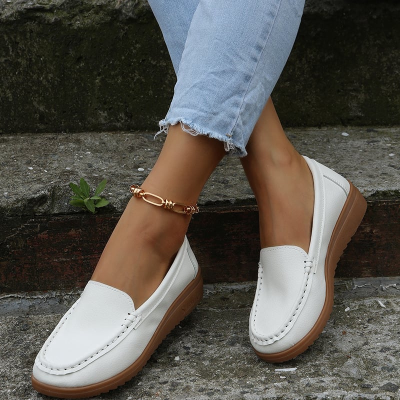 Weiße Damen-Loafer aus Leder mit brauner Sohle, getragen mit hellblauen Jeans. Elegante, bequeme Schuhe für Freizeit und Alltag.