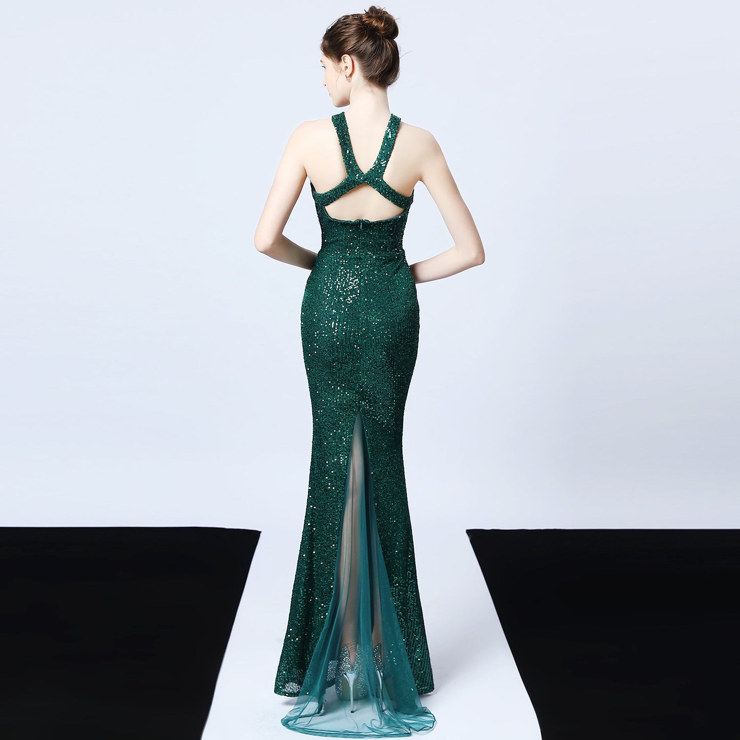 Frau in elegantem, grünem Paillettenkleid mit Rückenausschnitt und Schleppe, Abendmode, glamouröses Design, modisches Abendkleid.