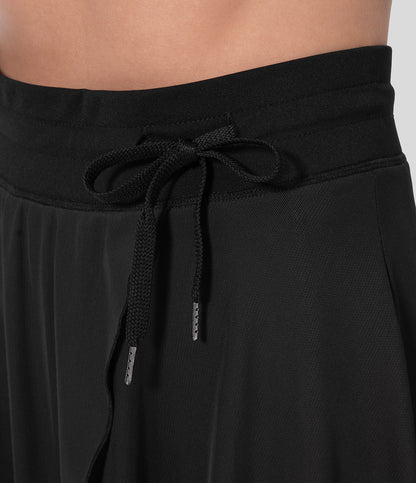 Schwarzer, plissierter Rock mit elastischem Bund und Kordelzug, Nahaufnahme. Modetrend, Damenbekleidung, eleganter Stil.
