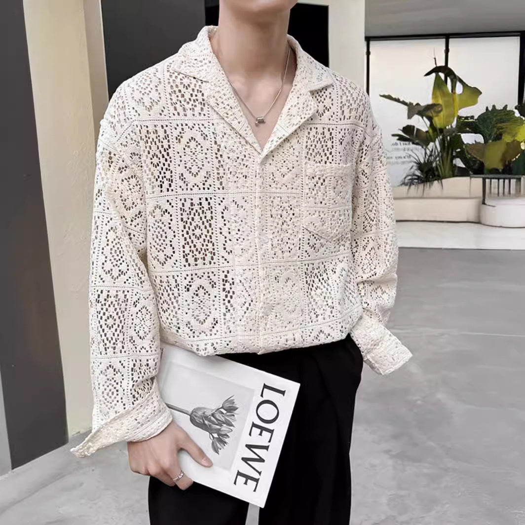 Person in weißer Häkelbluse hält ein Loewe-Magazin, steht in modernem Innenraum mit Pflanzen. Modetrend, Häkelmode, stilvolle Kleidung.