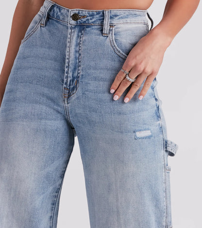 Frau trägt hoch taillierte, hellblaue Jeans mit weitem Bein; Hand mit Ringen auf Tasche. Modetrend, Damenjeans, lässiger Stil.