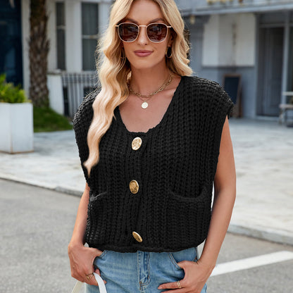 Frau mit blonder Welle, Sonnenbrille, schwarzer Strickweste mit großen Knöpfen, blauer Jeans, lässiger Straßenlook, modisch, urbaner Stil.