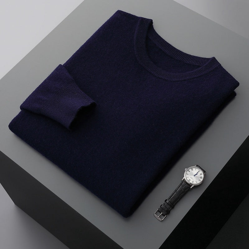 Dunkelblauer Pullover aus Kaschmir auf grauem Tisch, daneben eine elegante Armbanduhr mit schwarzem Lederarmband. Luxuriöse Modeaccessoires.
