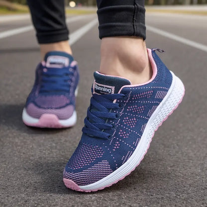 Dunkelblaue und rosa Laufschuhe auf Asphalt, Nahaufnahme. Bequeme Sportschuhe für Damen, ideal zum Joggen und Fitness.