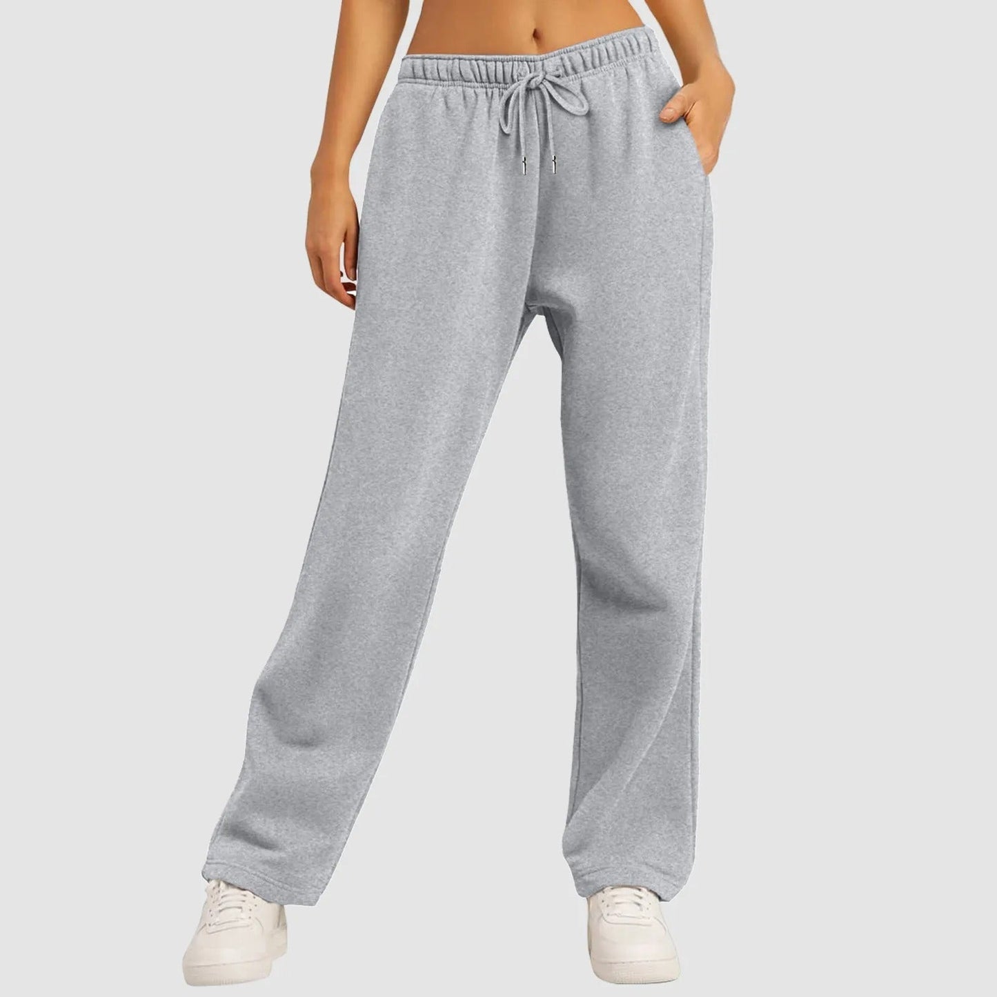 Graue Jogginghose Damen, bequem und lässig, mit Kordelzug, kombiniert mit weißen Sneakers. Ideal für Freizeit und Sport.
