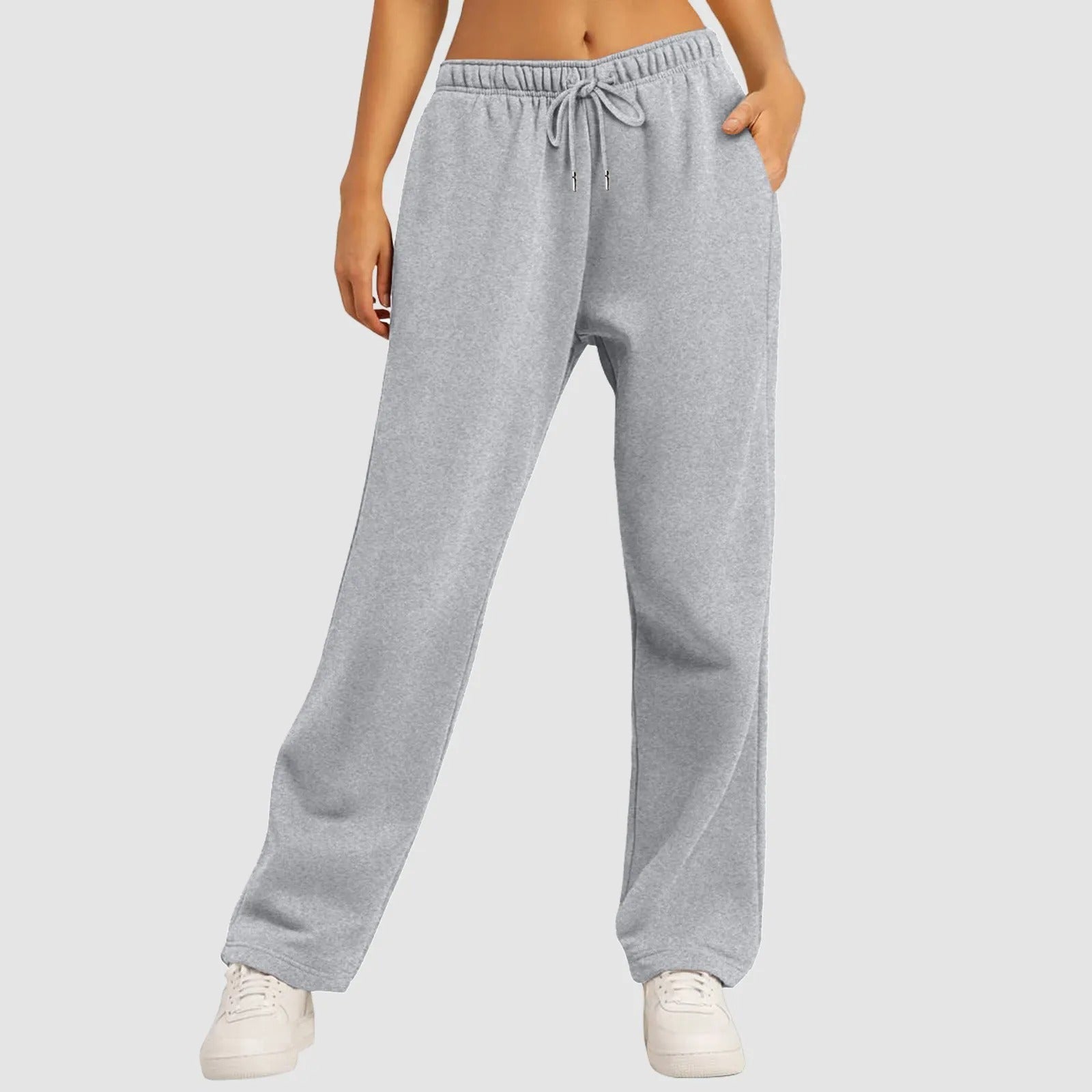 Graue Jogginghose Damen, bequem und lässig, mit Kordelzug, kombiniert mit weißen Sneakers. Ideal für Freizeit und Sport.