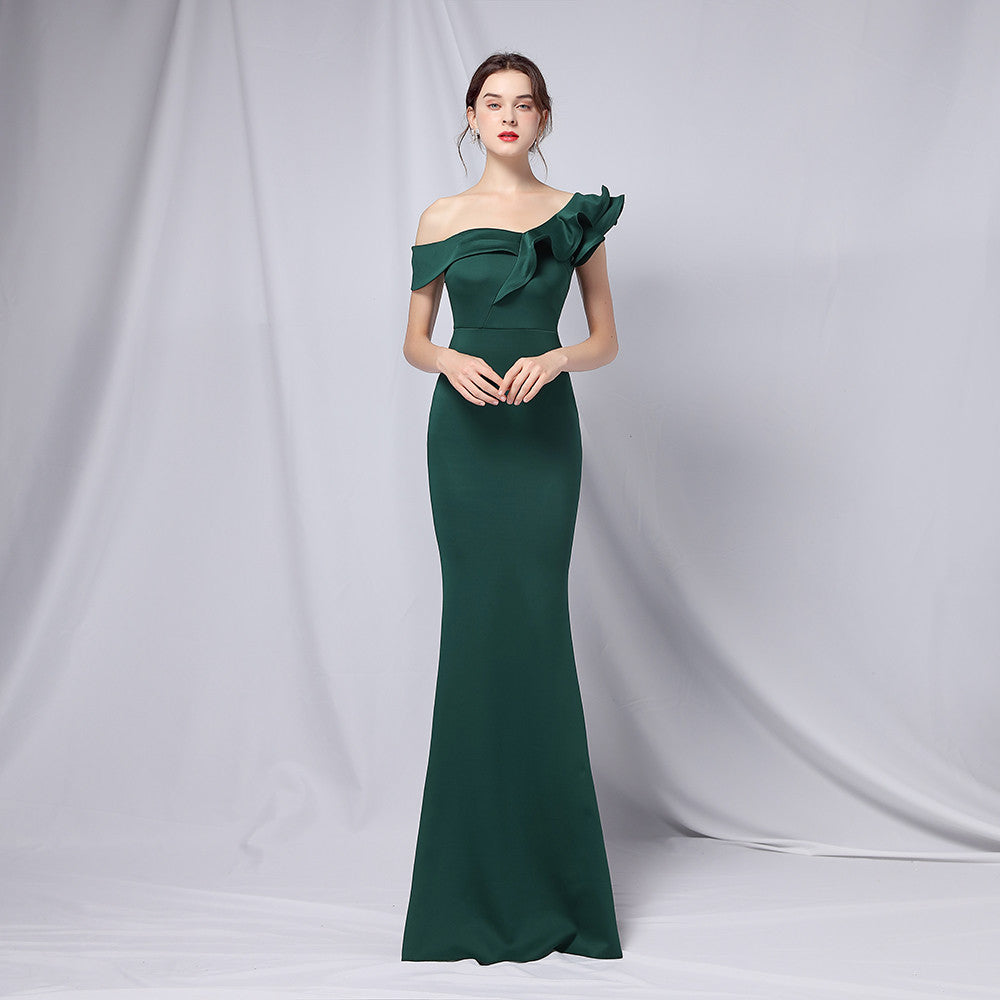 Frau in elegantem, schulterfreiem, smaragdgrünem Abendkleid mit Rüschen, posiert vor neutralem Hintergrund. Perfekt für Gala oder formelle Anlässe.