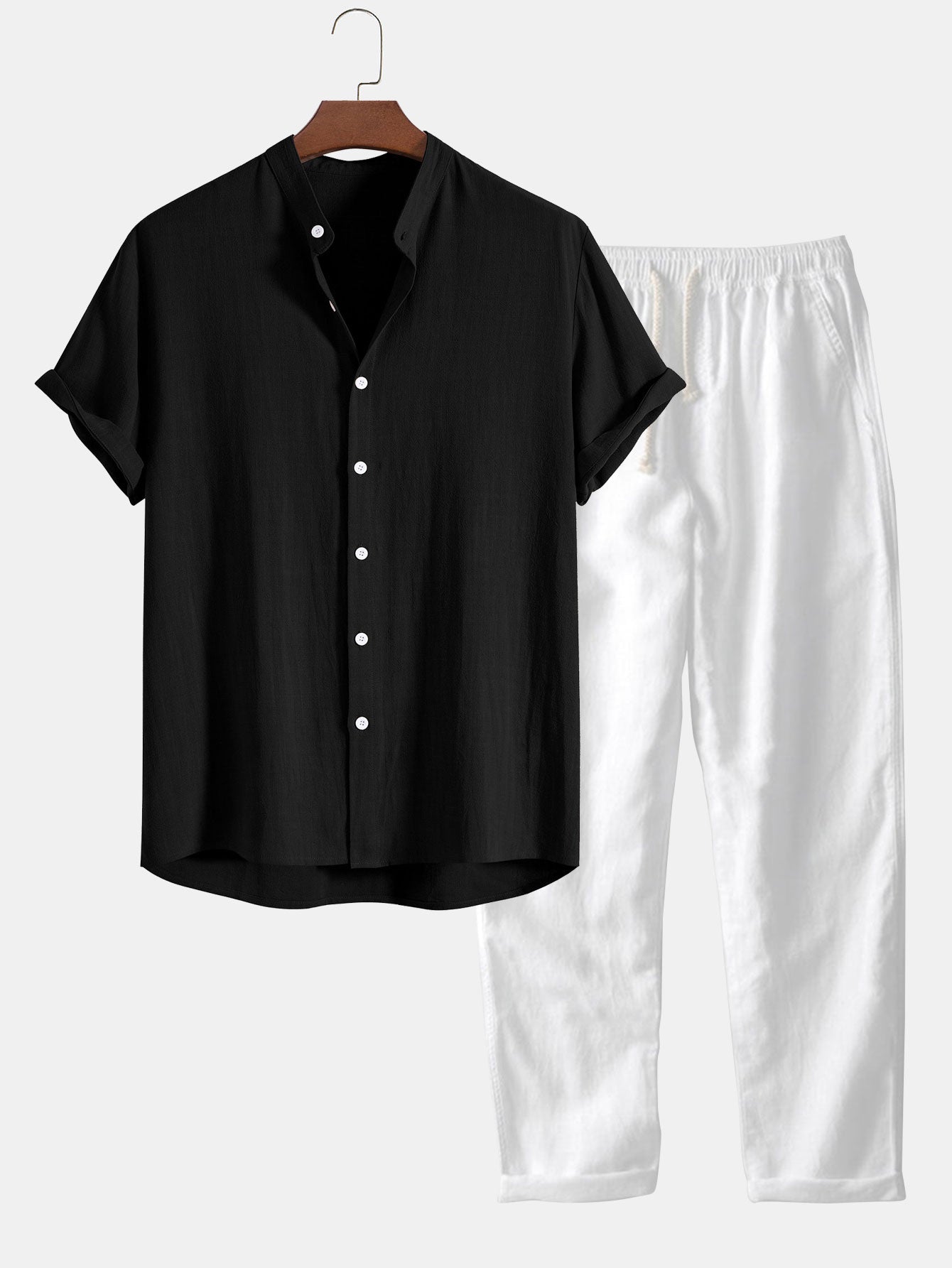 Schwarzes Kurzarmhemd mit Knopfleiste und weiße, locker sitzende Hose auf einem Kleiderbügel. Elegante, lässige Herrenmode.