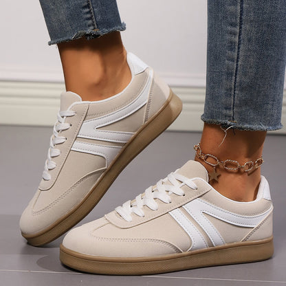 Damen Sneaker in Beige mit weißem Streifen, Gummisohle und Schnürsenkeln, getragen mit Jeans. Modische Freizeitschuhe für Alltag und Sport.