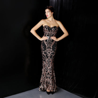 Frau in eleganter, schwarzer Abendkleid mit goldenen Verzierungen, posiert vor schwarzem Hintergrund. Glamouröse Mode, Abendgarderobe, Luxuskleid.