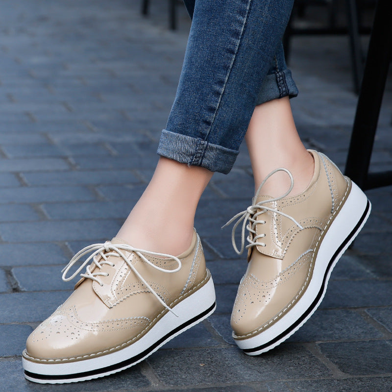 Beige Damen-Brogues mit Plateau, geschnürt, auf grauem Pflastersteinboden. Modische Schuhe, ideal für urbanen Stil und Komfort.