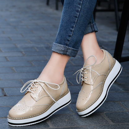 Beige Damen-Brogues mit Plateau, geschnürt, auf grauem Pflastersteinboden. Modische Schuhe, ideal für urbanen Stil und Komfort.