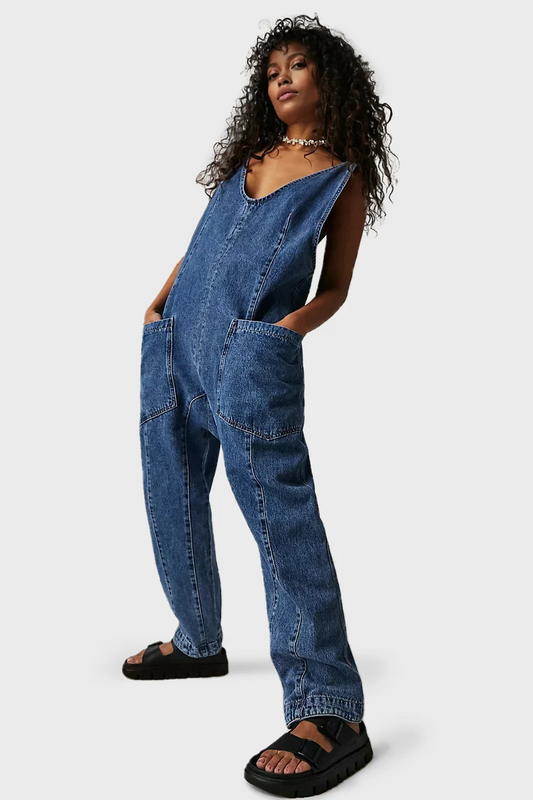 Frau in lässigem, blauem Denim-Overall mit V-Ausschnitt und Taschen, kombiniert mit schwarzen Sandalen. Modetrend, Streetwear, Damenmode.