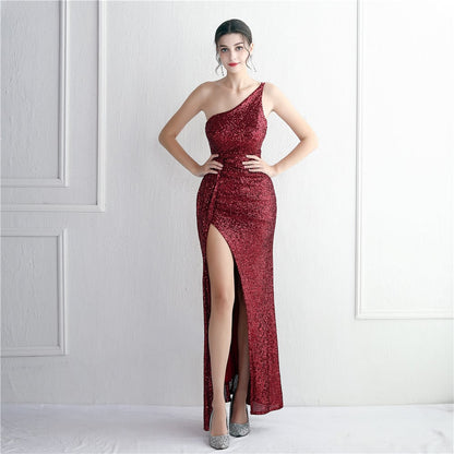 Frau in elegantem, rotem Paillettenkleid mit hohem Beinschlitz, posiert vor weißer Wand. Abendmode, glamouröses Design, festliche Kleidung.
