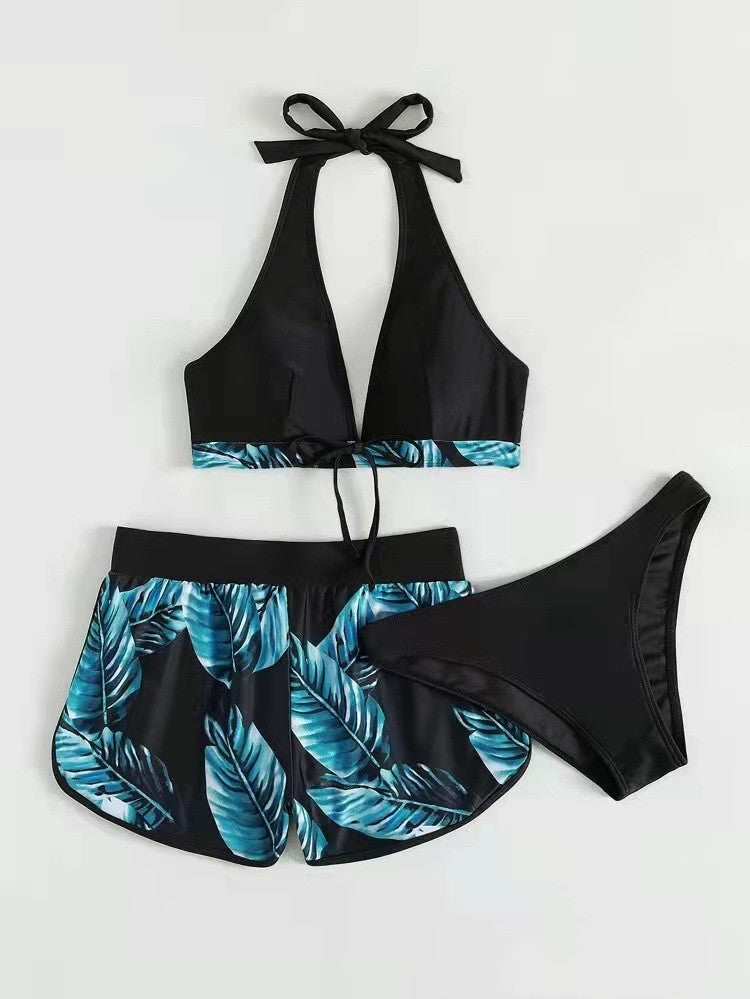 Damen-Bikini-Set mit tropischem Blattmuster, bestehend aus Triangel-Oberteil, Shorts und Slip in Schwarz und Blau. Ideal für Strand und Sommer.