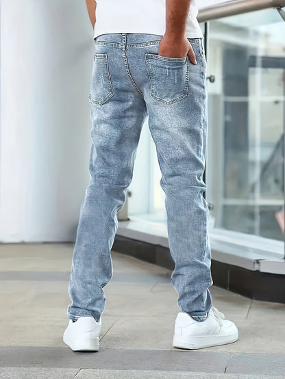 Rückansicht eines Mannes in hellblauen Jeans und weißen Sneakers, stehend in modernem Innenraum. Modetrend, Freizeitkleidung, Herrenjeans.