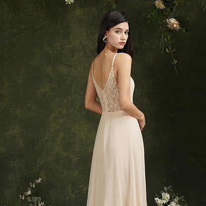 Frau in eleganter, cremefarbener Abendkleid mit Spitzenrücken, vor grünem, floralem Hintergrund. Perfekt für Hochzeiten oder formelle Anlässe.