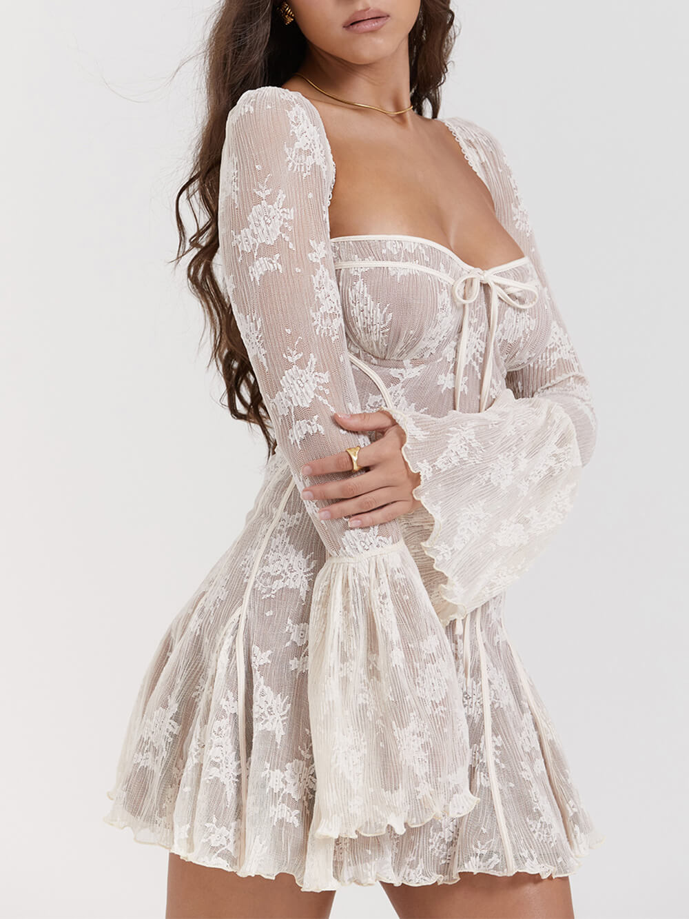 Frau in weißem, langärmligem Spitzenkleid mit Blumenmuster und ausgestellten Ärmeln. Elegantes Design, modische Damenbekleidung, Abendmode.