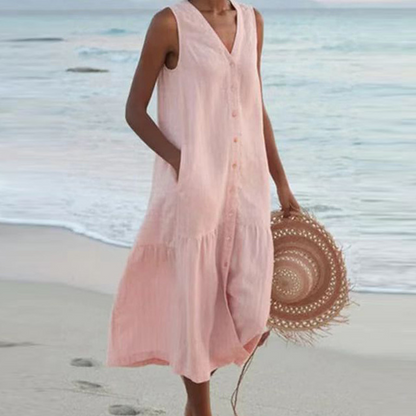 Frau in rosa Sommerkleid am Strand, hält runden Strohhut. Strandmode, Sommerkleid, Damenbekleidung, Urlaubsoutfit, Strandspaziergang.