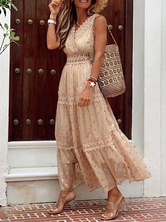 Frau in langem, ärmellosem Sommerkleid mit Spitze, trägt Strohhut und geflochtene Tasche, steht vor Holztür. Elegante Sommermode, Boho-Stil.