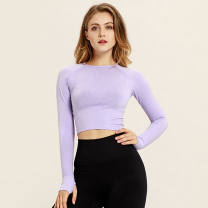 Junge Frau in lila Sportoberteil und schwarzer Leggings, Fitnessmode, Langarm, athletische Kleidung, Studioaufnahme.