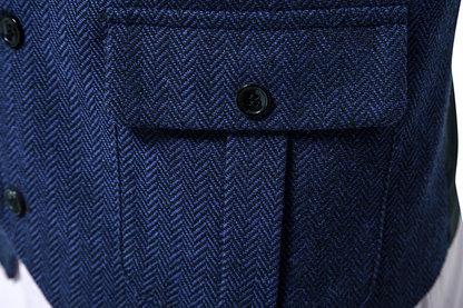 Nahaufnahme einer blauen Fischgrät-Jacke mit schwarzen Knöpfen und einer Tasche. Hochwertige Herrenmode, elegantes Design, stilvolle Textur.
