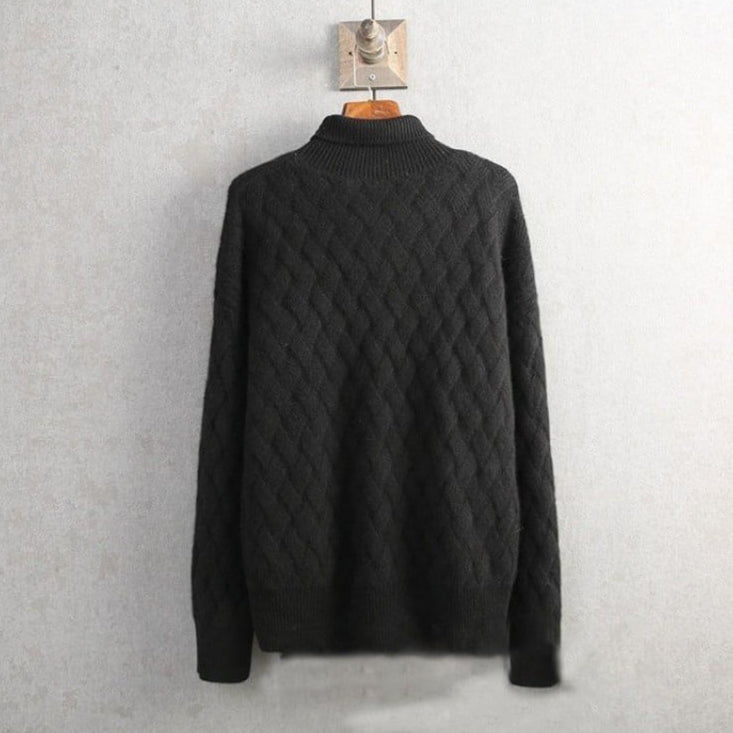 Schwarzer Strickpullover mit Zopfmuster, hängend an Holzbügel vor grauer Wand. Modischer Herrenpullover, warm und stilvoll für Herbst und Winter.
