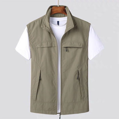 Beige Herrenweste mit Reißverschluss über weißem T-Shirt, hängend auf Holzkleiderbügel. Outdoor-Mode, Freizeitkleidung, ärmellose Jacke.