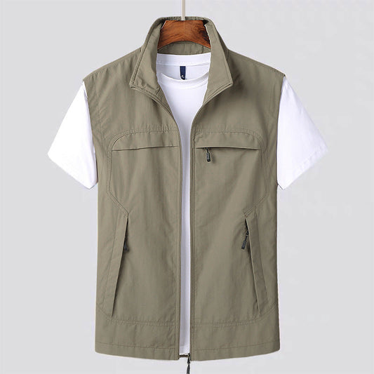 Beige Herrenweste mit Reißverschluss über weißem T-Shirt, hängend auf Holzkleiderbügel. Outdoor-Mode, Freizeitkleidung, ärmellose Jacke.
