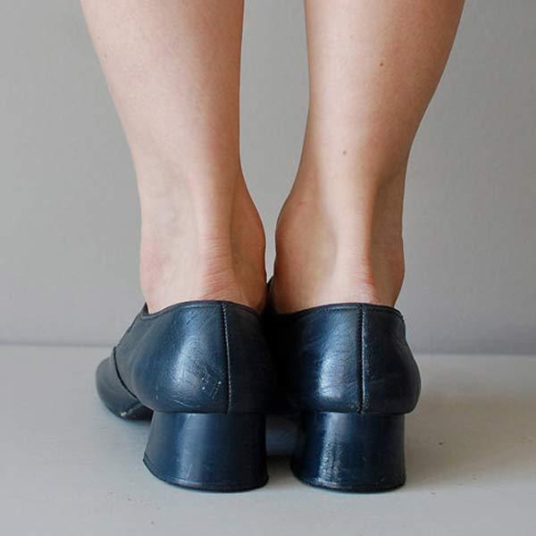 Damenfüße in schwarzen Lederschuhen mit Blockabsatz, Rückansicht. Elegante, bequeme Schuhe für Büro und Alltag. Mode, Damenmode, Schuhe.