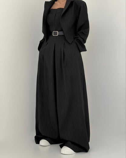 Schwarzer Nadelstreifen-Hosenanzug mit Gürtel, kombiniert mit weißen Sneakern. Eleganter, moderner Business-Look für Damen.