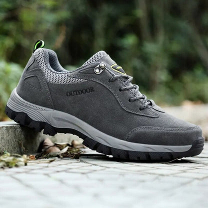 Grauer Outdoor-Wanderschuh auf steinigem Weg, atmungsaktives Mesh, rutschfeste Sohle, ideal für Trekking und Naturabenteuer.