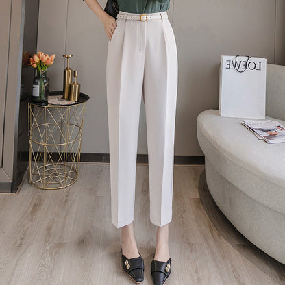 Damenhose in Weiß, elegant und modern, kombiniert mit schwarzen Loafers. Stilvolle Einrichtung im Hintergrund mit Blumen und Zeitschriften.