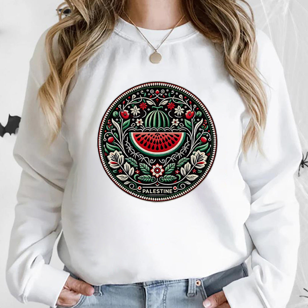 Frau trägt weißen Pullover mit palästinensischem Mandala-Design, Wassermelonenmotiv, traditionelles Kunstwerk, ethnische Mode, Nahost-Kultur.