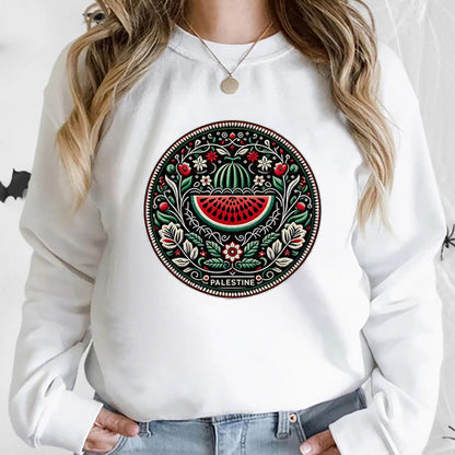 Frau trägt weißen Pullover mit palästinensischem Mandala-Design, Wassermelonenmotiv, traditionelles Kunstwerk, ethnische Mode, Nahost-Kultur.