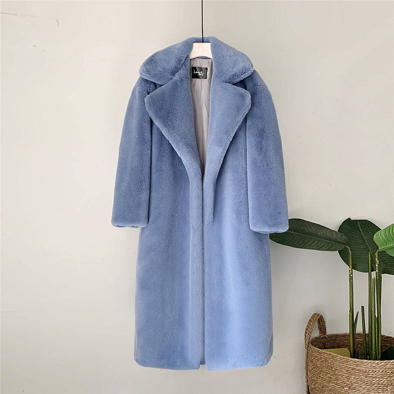 Hellblauer Kunstpelzmantel auf Kleiderbügel, elegantes Design, weiches Material, modischer Wintermantel, Damenbekleidung, vor weißer Wand.