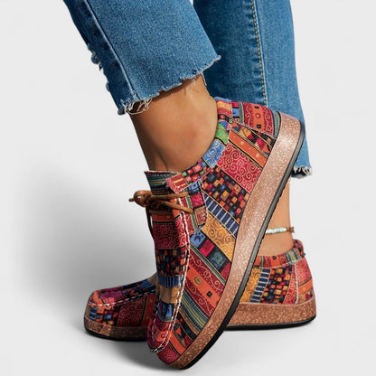 Bunte Patchwork-Sneaker mit flacher Sohle, getragen von Person in blauen Jeans. Modische, bequeme Freizeitschuhe für Damen.