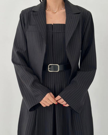 Frau in schwarzem Nadelstreifenanzug mit Gürtel, elegantes Business-Outfit, modischer Blazer, professionelle Damenbekleidung.