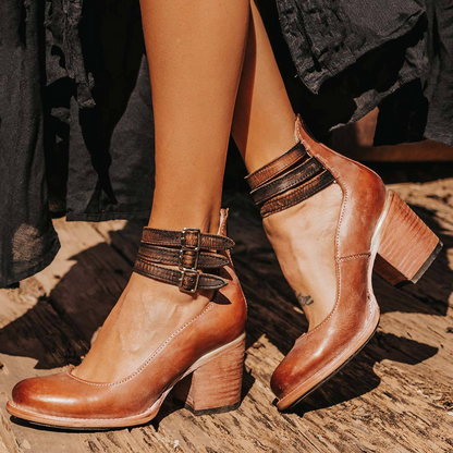 Braune Lederstiefeletten mit Blockabsatz und Schnallen, getragen von einer Person in schwarzem Rock. Modische Damenstiefel für Herbstmode.