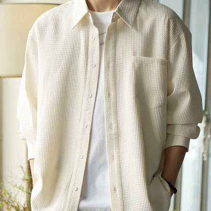 Beige Herrenhemd mit Waffelmuster, lässig über weißem T-Shirt getragen. Modetrend, Herrenbekleidung, stilvolles Outfit, Freizeitlook.