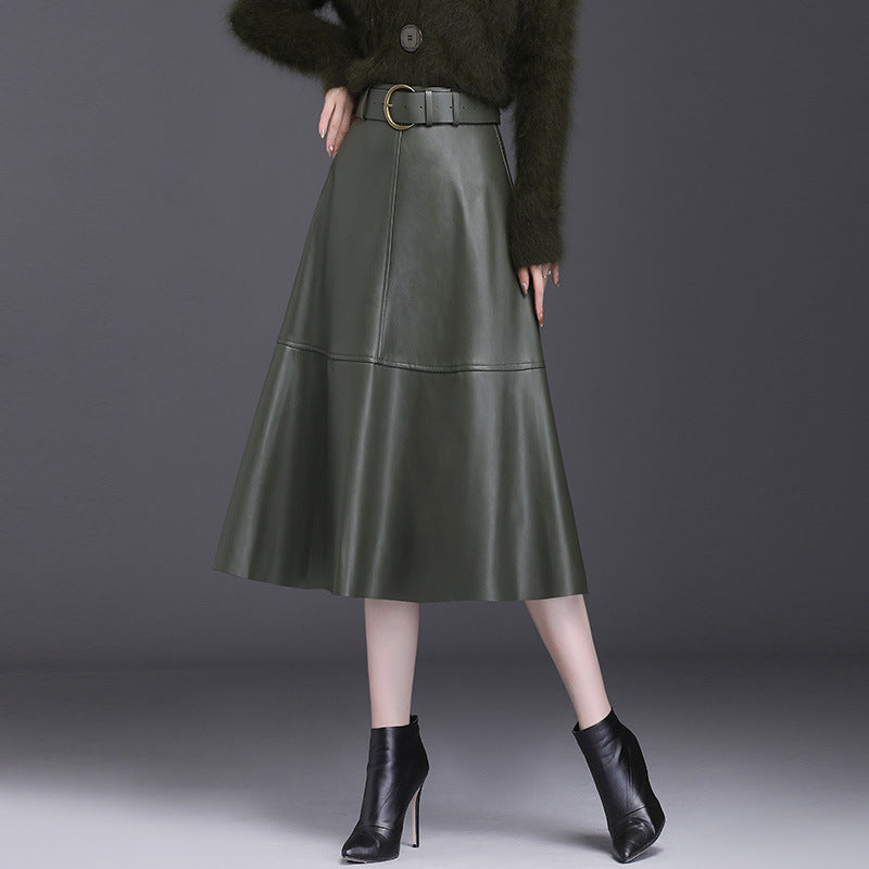 Damen A-Linien-Lederrock in Dunkelgrün, knielang, mit Gürtel. Kombiniert mit schwarzen Stiefeletten. Elegante Herbstmode für Frauen.