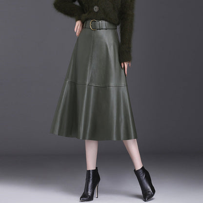 Damen A-Linien-Lederrock in Dunkelgrün, knielang, mit Gürtel. Kombiniert mit schwarzen Stiefeletten. Elegante Herbstmode für Frauen.