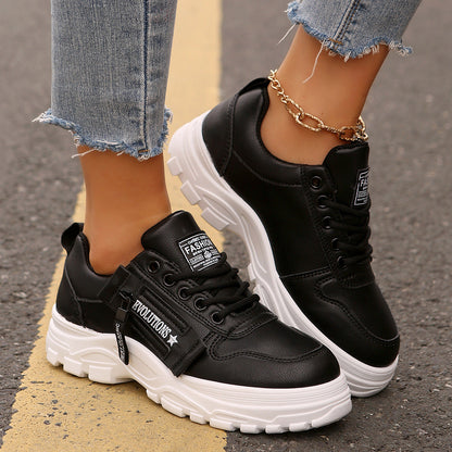 Schwarze Damen-Sneaker mit weißer Sohle, getragen mit zerrissenen Jeans. Modische Straßenschuhe, ideal für lässige Outfits und urbanen Stil.