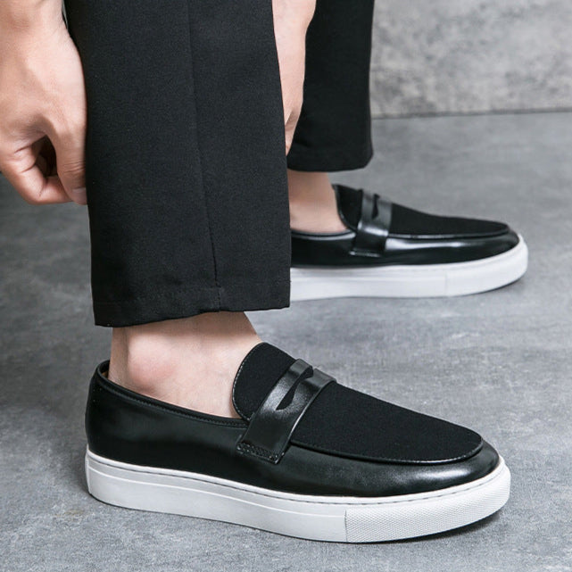 Schwarze Herren-Sneaker aus Leder mit weißer Sohle, getragen zu schwarzer Hose. Stilvolle, bequeme Freizeitschuhe für den Alltag.