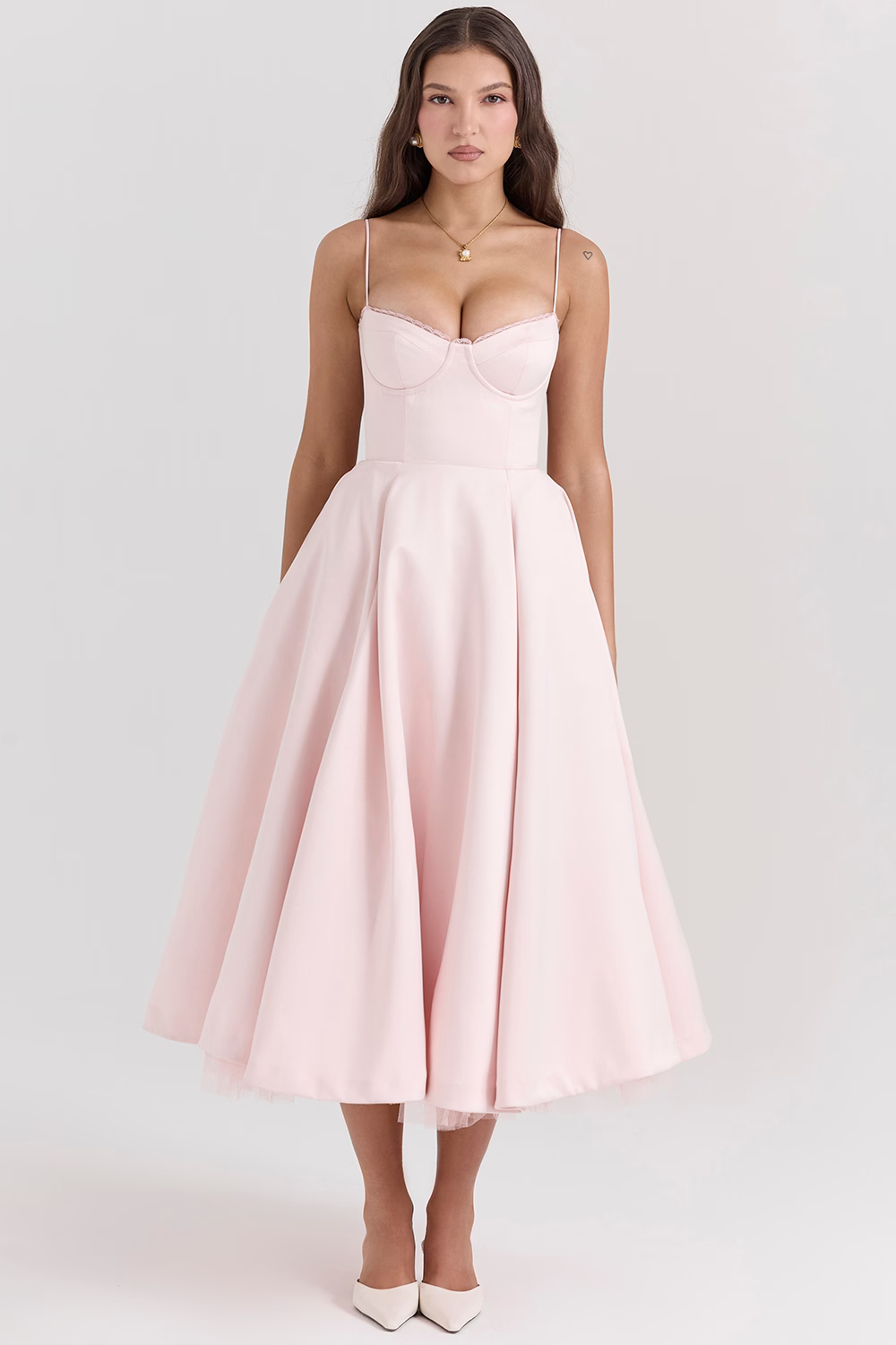 Frau in rosa Cocktailkleid mit Spaghettiträgern und ausgestelltem Rock, elegante Abendmode, perfekte Wahl für festliche Anlässe.
