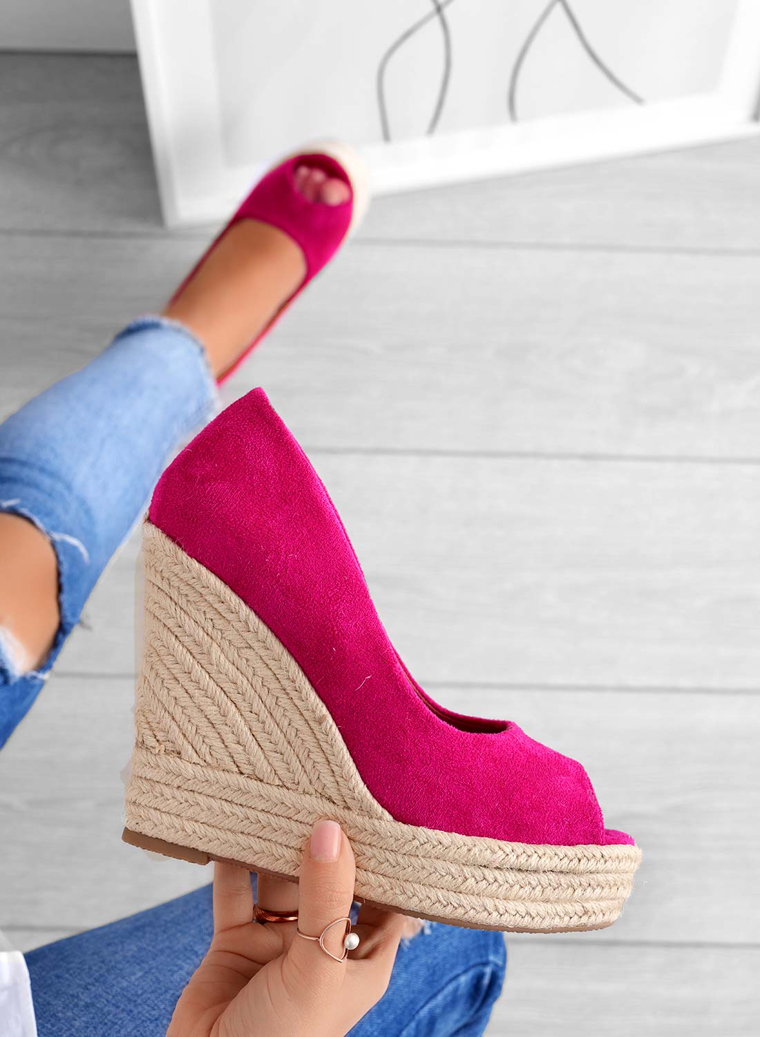 Fuchsia Keilsandalette mit Bastsohle, gehalten von Hand. Perfekt für Sommermode, kombiniert mit zerrissenen Jeans. Trendige Damenmode, stilvoll und modern.