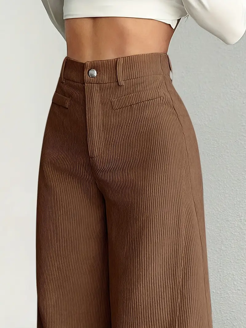 Braune, gerippte High-Waist-Hose aus Cordstoff, getragen von einer Person mit weißem Oberteil. Modetrend, Damenbekleidung, stilvolle Herbstmode.