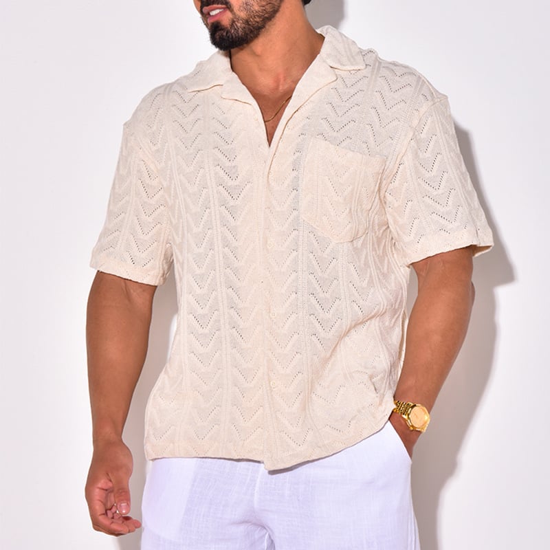 Mann trägt cremefarbenes, gehäkeltes Kurzarmhemd mit V-Ausschnitt und Brusttasche. Sommermode, lässiger Stil, Herrenbekleidung.