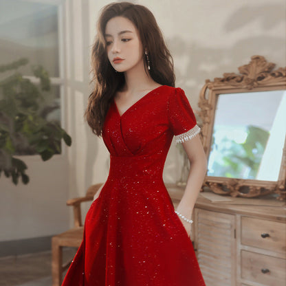 Frau in elegantem, funkelndem roten Kleid vor antikem Spiegel, stilvolle Abendmode, glamouröses Design, luxuriöse Inneneinrichtung.