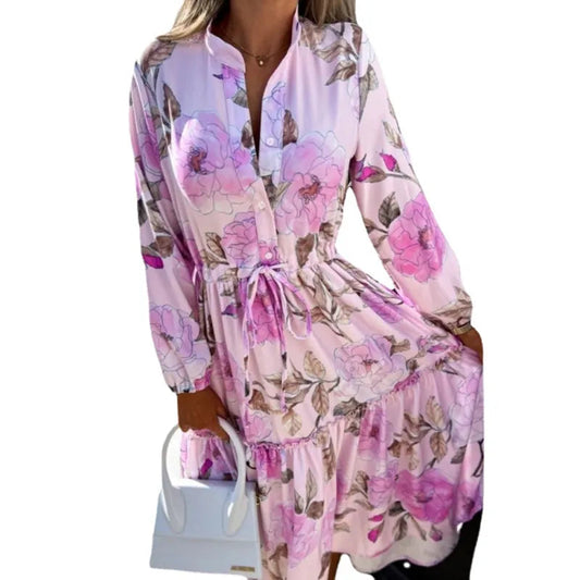 Frau in rosa geblümtem Kleid mit langen Ärmeln, hält weiße Handtasche. Modetrend, Damenmode, florales Design, elegantes Outfit.